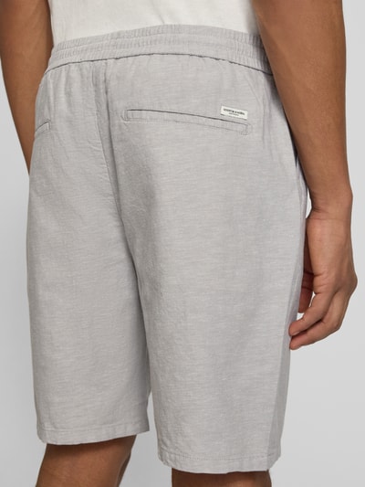 Männermodel trägt Shorts mit elastischem Bund von Scotch & Soda aus Baumwoll-Leinen-Mix in Hellgrau, Regular Fit, Rückansicht.