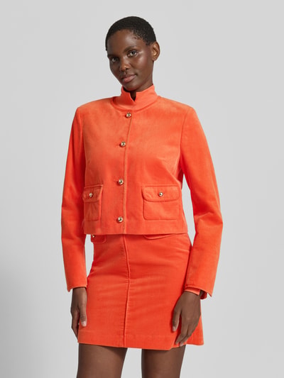 Frauenmodel trägt Regular Fit Kurzblazer aus reiner Baumwolle von Marc Cain in leuchtendem Orange, Cord, Rundhalsausschnitt, Knopfleiste, Pattentaschen, Ganzkörperansicht von vorne.