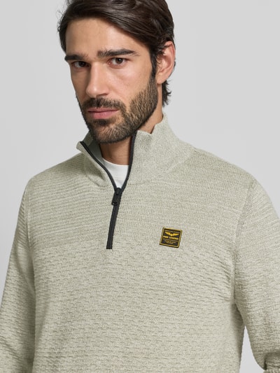 Männermodel trägt Strickpullover mit Stehkragen von PME Legend in Beige mit kurzem Reißverschluss, Label-Detail, Nahaufnahme Oberkörper.