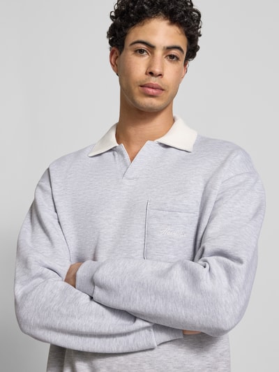 Mannelijk model draagt Sweatshirt mit Kontrastkragen und Brusttasche mit Logo-Bestickung van REVIEW in lichtgrijs, katoenmix, regular fit, borstzak met geborduurd logo, ruglengte maat M 71 cm, mouwlengte maat M 63 cm, Nahaufnahme bovenlichaam