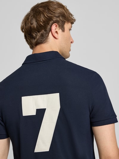 Männermodel trägt Regular Fit Poloshirt mit Logo-Stitching von REVIEW, Reine Baumwolle, Polokragen, Kurzärmelig, Rückenlänge 65 cm, Ganzkörperansicht Rückansicht.
