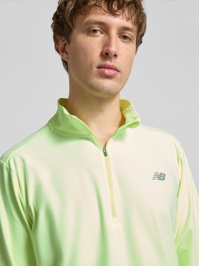 Męski model nosi Regular Fit Sweatshirt mit Troyer-Kragen od New Balance, elastyczna mieszanka materiałów, nadruk z logo, zbliżenie na górę ciała