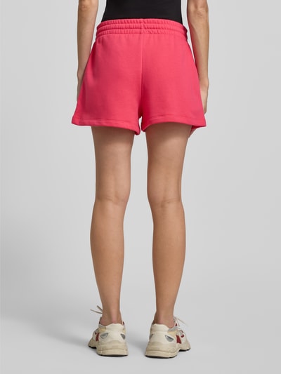Frauenmodel trägt Sweatshorts mit Logo und elastischem Bund von GAP in kräftigem Pink, Baumwoll-Mix, Regular-Fit, Ganzkörperansicht Rückansicht.