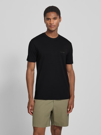 Männermodel trägt Extra Slim Fit T-Shirt mit Rundhalsausschnitt von Armani Exchange in Schwarz mit Logo, Rückenlänge 70 cm, Ganzkörperansicht von vorne.