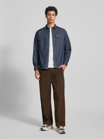 Męski model nosi Regular Fit Freizeithemd aus Baumwolle od Replay, koszula casualowa z bawełny, krój regular fit, kołnierzyk typu kent, na całej długości listwa guzikowa, kieszenie na piersi z guzikiem, detal z logo, długość tyłu w rozmiarze M: 75 cm, szerokość ramion w rozmiarze M: 39 cm, długość rękawów w rozmiarze M: 65 cm, odcień ciemnoniebieski, struktura gładka, kształty proste, całkowity widok z przodu