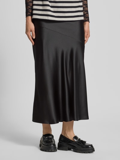 Frauenmodel trägt Satinrock mit elastischem Bund von Gina Tricot in Schwarz mit Gerader-Schnitt, Maxirock, Satin-Haptik, Nahaufnahme Unterkörper.