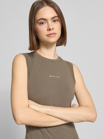 Frauenmodel trägt Slim Fit Top aus Lyocell-Baumwoll-Mix Modell 'Lenox' von P.E Nation mit Logo-Print, Rundhalsausschnitt, braun, Nahaufnahme Oberkörper. Rückenlänge bei Größe S: 47 cm.