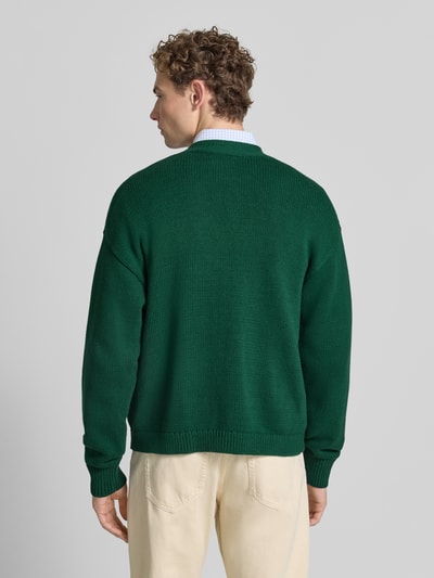 Männermodel trägt Relaxed Fit Strickjacke aus reiner Baumwolle von Polo Ralph Lauren in Dunkelgrün, Strukturstrick, Ganzkörperansicht Rückansicht.