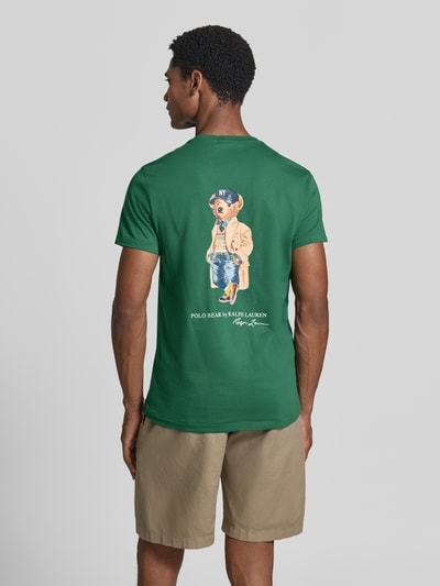 Männermodel trägt Slim Fit T-Shirt aus reiner Baumwolle mit polo bear-print von Polo Ralph Lauren in groen, beige shorts, Ganzkörperansicht Rückansicht, heren t-shirt van Polo Ralph Lauren