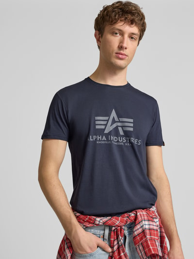 Männermodel trägt dunkelblaues Herren T-Shirt mit Label-Detail Modell 'BASIC' von Alpha Industries aus Reiner Baumwolle, Gerader-Schnitt, Rundhalsausschnitt, Rückenlänge bei Größe M 69 cm, Ganzkörperansicht von vorne.