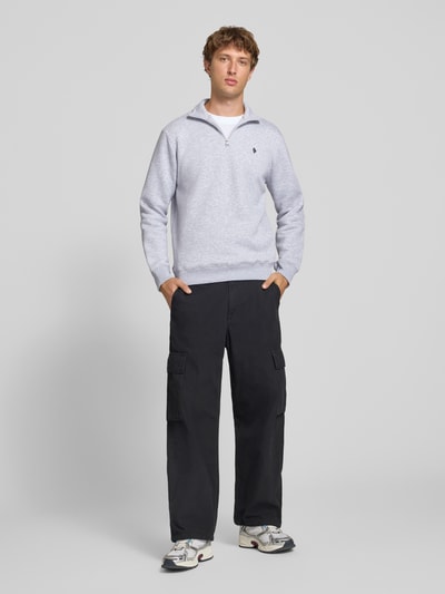 Männermodel trägt Slim Fit Sweatshirt aus reiner Baumwolle von REVIEW in Hellgrau, gerippte Abschlüsse, Troyer-Kragen, Ganzkörperansicht von vorne.