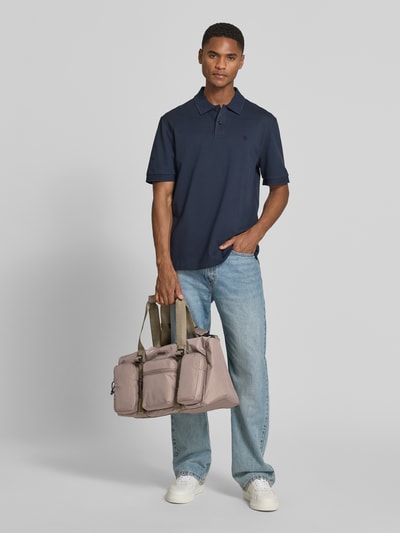 Männermodel trägt Weekender mit Reißverschlusstaschen Modell 'EVERETT' von HUGO, Mehrfarbig, Logo-Print, Henkel, Schulterriemen, Ganzkörperansicht von vorne.