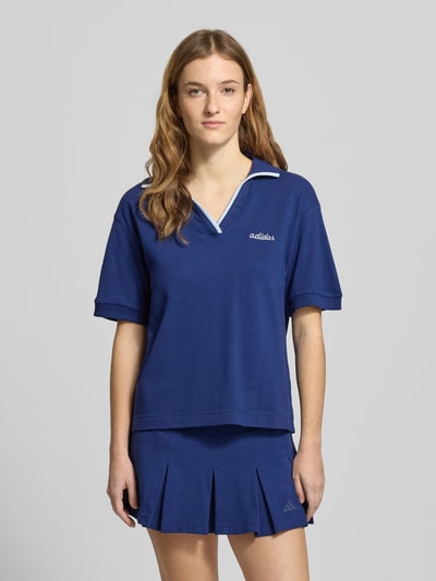 Frauenmodel trägt Poloshirt mit Label-Stitching von adidas Sportswear in Dunkelblau, lockerer Schnitt, reine Baumwolle, Ganzkörperansicht von vorne.