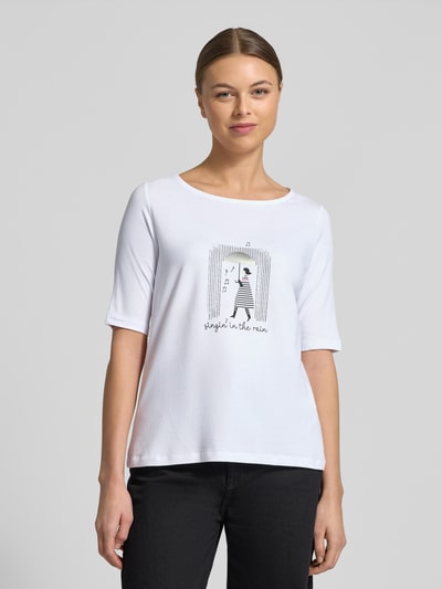 Vrouwenmodel draagt Regular fit T-shirt met strass-steendecoratie model 'Januar' van More & More, wit met print, halflange mouw, ronde hals, elastische katoenmix met modal, ruglengte 61 cm bij maat 36, close-up bovenlichaam vooraanzicht.