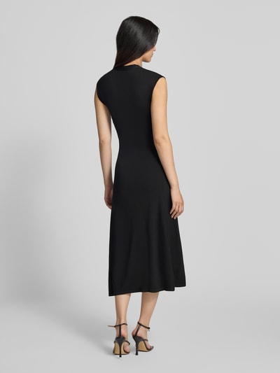 Frauenmodel trägt Kleid aus Viskose-Mix Modell 'CANELONS' von MANGO in Schwarz, taillierte Passform, Midilänge, Ganzkörperansicht Rückansicht.