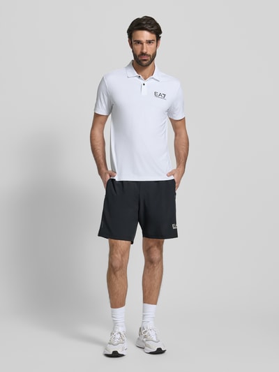 Männermodel trägt Shorts mit elastischem Bund und Logo von EA7 Armani, Material-Mix mit Stretch-Anteil, Regular-Fit, Eingrifftaschen, Ganzkörperansicht von vorne.