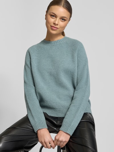 Frauenmodel trägt Regular Fit Strickpullover aus Alpaka-Mix mit Baumwoll-Anteil Modell 'FEBISAN' von BOSS in Hellblau, unifarben, grob gestrickt, Rundhals, gerippte Bündchen, Ganzkörperansicht von vorne.