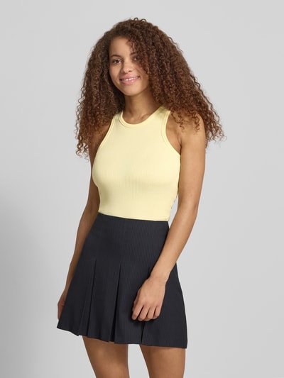Frauenmodel trägt Slim Fit Tank Top aus Baumwoll-Mix Modell 'RUKA BOXER' von Pieces in unifarbenem Gelb, breite Träger, Rippstruktur, Nahaufnahme Oberkörper.
