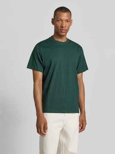 Męskki model nosi Relaxed Fit T-Shirt aus reiner Baumwolle Modell 'ASPEN' von SELECTED HOMME, ciemnozielony, gładki, Ganzkörperansicht von vorne.