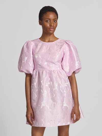 Frauenmodel trägt Cocktailkleid mit Puffärmeln Modell 'NOEALLA' von YAS, A-Linie, Minikleid, zart rosa mit floralem Muster, Nahaufnahme Oberkörper.