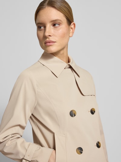Kobiece modelka nosi Trenchcoat mit Knopfverschluss od MICHAEL Michael Kors, kolor beżowy, krój regular fit, dwurzędowy, kołnierz wykładany, szerokość w rozmiarze S: 52 cm, długość pleców: 61 cm, długość rękawa: 63 cm, szerokość ramion: 40 cm, faktura gładka, zbliżenie na górną część tułowia, widok z przodu