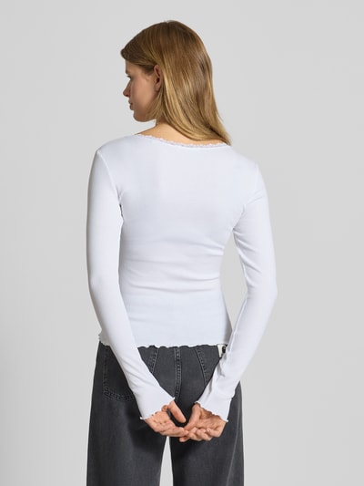 Frauenmodel trägt Longsleeve mit Rundhalsausschnitt von Review, weiß, Slim Fit, Baumwoll-Elasthan-Mix, Muschelsaum, Schleifen-Detail, Rückenlänge 50 cm bei Größe S, Ganzkörperansicht Rückansicht.