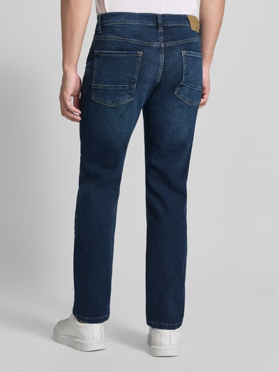 Męski model nosi Regular Fit Jeans mit Eingrifftaschen von MCNEAL, mieszanka bawełny i elastanu, efekt znoszenia, wpuszczane kieszenie, Szerokość w rozmiarze 32/32: 45 cm, Długość wewnętrzna nogawki 80 cm, ciemnoniebieski, prosty fason, tekstura dżinsu, pełny widok sylwetki od tyłu