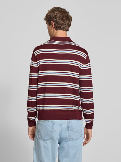 Männermodel trägt Strickpullover mit Polokragen von REVIEW in Bordeaux mit weißen Streifen, lockere Passform, Ganzkörperansicht Rückansicht.