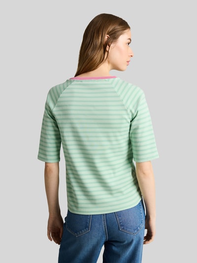 Frauenmodel trägt Shaped Fit T-Shirt aus reiner Baumwolle von Tom Tailor Denim, Optik: Unifarben, Muster: Gestreift, Label-Stitching-Applikation, Herz-Stitching, Rundhals, Ärmelform: Kurzarm, Materialverarbeitung: Feinripp, Ganzkörperansicht Rückansicht.