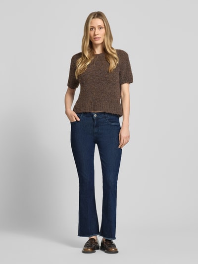 Frauenmodel trägt Bootcut Jeans mit Fransen Modell 'SHAKIRA' von Brax aus Baumwoll-Mix mit Stretch-Anteil, Dunkelblau, Eingrifftaschen, Knopf- und Reißverschluss, verkürzte Passform, Fransen-Saum, Ganzkörperansicht von vorne.