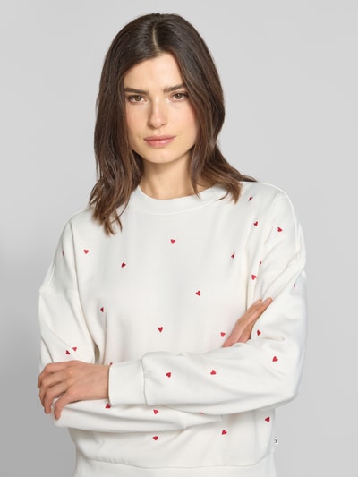 Frauenmodel trägt Regular Fit Sweatshirt aus reiner Baumwolle von Tom Tailor Denim, unifarben, mit allover roten Stickereien, Nahaufnahme Oberkörper.