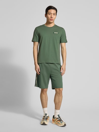 Męski model ma na sobie Regular Fit T-Shirt mit Logo-Patch od EA7 Emporio Armani, bawełna, krój regular fit, dekolt okrągły, długość pleców w rozmiarze M: 52 cm, pełny widok z przodu