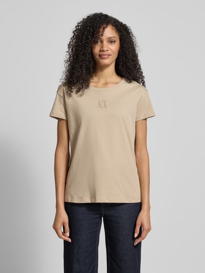 Frauenmodel trägt T-Shirt aus reiner Baumwolle von Armani Exchange in Beige, gerader Schnitt, Rundhalsausschnitt, Label-Detail, Strasssteinbesatz, Damen T-Shirt; Ganzkörperansicht von vorne. Rückenlänge bei Größe S: 59 cm.