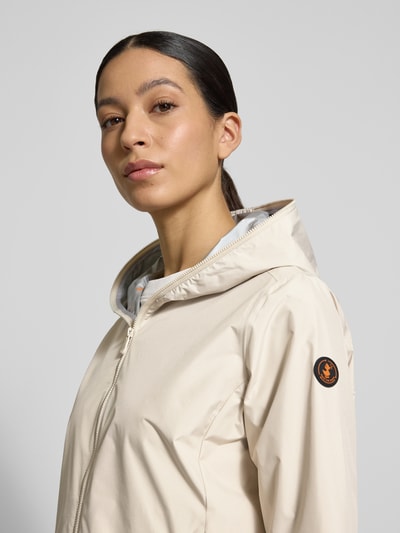 Frauenmodel trägt Regular Fit Jacke mit Zweiwegereißverschluss Modell 'Stella' von SAVE THE DUCK, cremefarben, glatte Textur, Nahaufnahme Oberkörper. Im Kontext: Damenjacke mit Zweiwegereißverschluss, Eingrifftaschen, Größe S mit 60 cm Rückenlänge, 42 cm Schulterbreite, 52 cm Brustweite, 64 cm Ärmellänge.