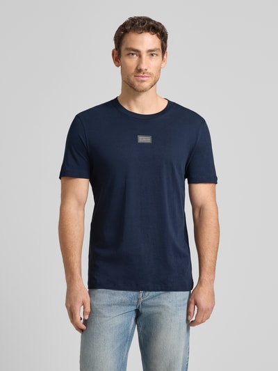 Männermodel trägt Regular Fit T-Shirt aus reiner Baumwolle von Tom Tailor Denim in Dunkelblau, unifarben, Label-Schriftzug, Ganzkörperansicht von vorne.
