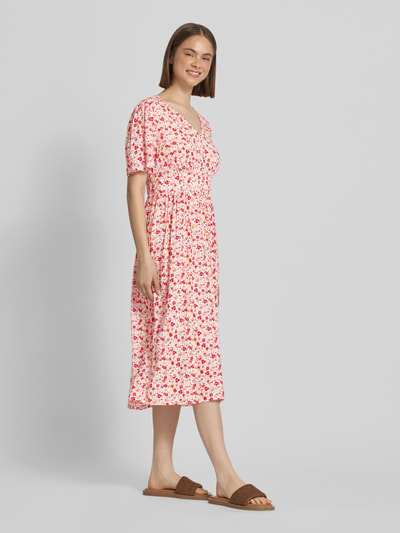 Frauenmodel trägt A-Linien Midikleid aus reiner Viskose Modell 'TALA' von Pieces, Allover-Muster in Rosa und Rot, Ganzkörperansicht von vorne.