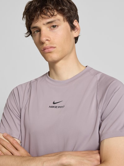Männermodel trägt T-Shirt mit Logo-Print und Raglanärmeln von NIKE TRAINING in Flieder, Straight Fit, Rundhalsausschnitt, Nahaufnahme Oberkörper