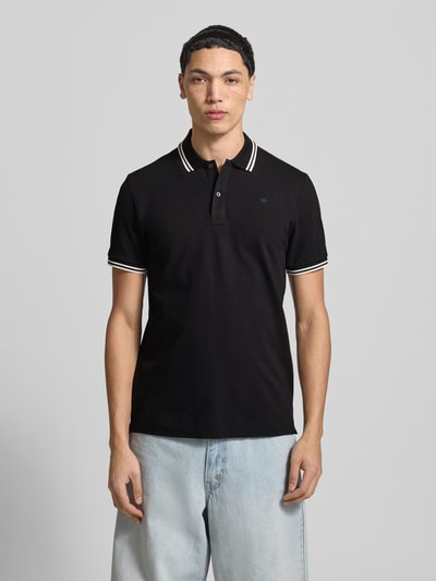 Männermodel trägt Slim Fit Poloshirt mit Logo-Stitching Modell 'Dunda' von G-Star Raw, schwarzer Baumwoll-Mix, Polokragen, Ganzkörperansicht von vorne.