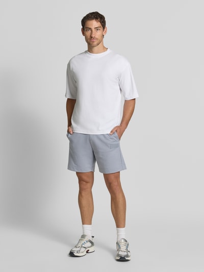 Männermodel trägt Regular Fit Sweatshorts aus Baumwoll-Mix Modell 'JT_SHORTS' von BOSS für BOSS Green, hellgrau, Ganzkörperansicht von vorne.