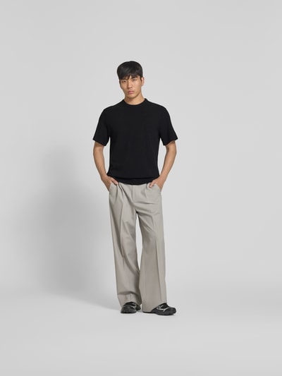 Männermodel trägt Relaxed Fit T-Shirt mit Strukturmuster von Forét aus Reine Baumwolle, Logo-Stitching, Rundhalsausschnitt, schwarze Farbe, Rückenlänge bei Größe M: 69 cm, Ganzkörperansicht von vorne.