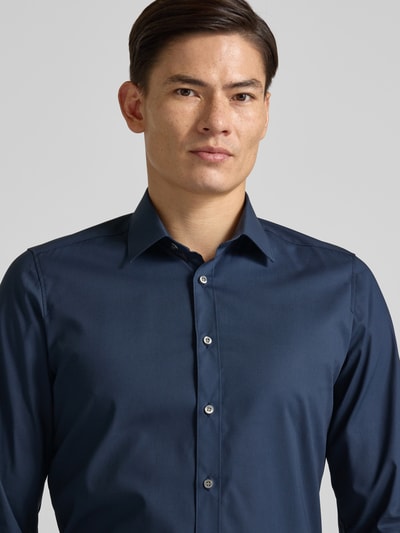 Männermodel trägt Body Fit Business-Hemd mit Knopfleiste von OLYMP Level Five, dunkelblau, Baumwoll-Elasthan-Mix, Nahaufnahme Oberkörper. Rückenlänge bei Größe 40: 80 cm, Schulterbreite bei Größe 40: 42 cm, Ärmellänge bei Größe 40: 68 cm, Kentkragen.