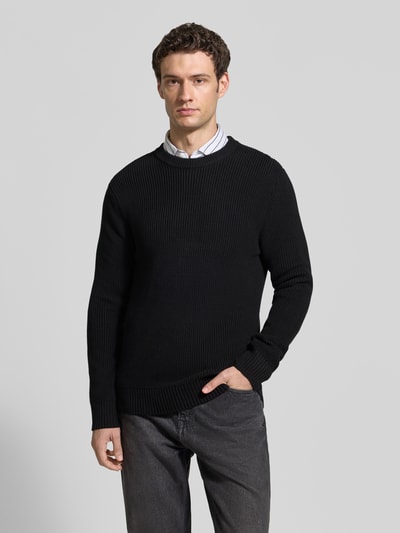 Männermodel trägt Regular Fit Strickpullover aus reiner Baumwolle von MCNEAL, dunkle Farben, Rundhalsausschnitt, Ganzkörperansicht von vorne.