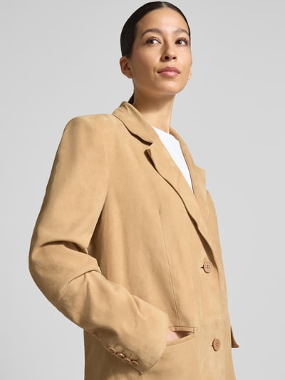 Frauenmodel trägt Ledermantel mit Pattentaschen Modell 'Santara' von STAND STUDIO aus echtem Ziegenvelours, sandfarben, Reverskragen, Knopfverschluss, glatte Textur, gerader Schnitt, Nahaufnahme Oberkörper.