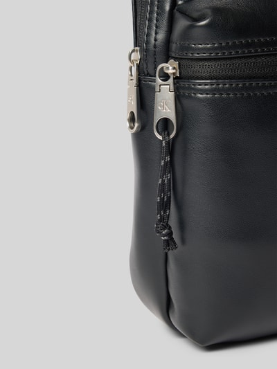 Produktfoto, Herren Umhängetasche mit Label-Prägung von CK Calvin Klein, schwarzes glattes Material mit silbernem Reißverschluss, kontekst: Herren Umhängetasche von CK Calvin Klein