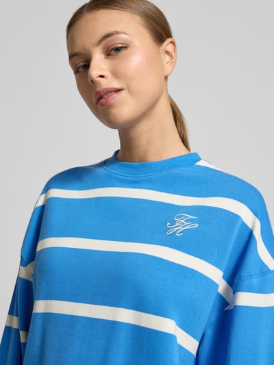 Vrouwenmodel draagt Relaxed Fit Sweatshirt aus Baumwoll-Mix van Tommy Hilfiger met blauw-wit streeppatroon, logo-stiksel, ronde hals, lange mouwen, katoenmix sweatmateriaal, detailopname bovenlichaam.