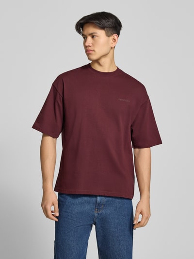 Männermodel trägt Oversized T-Shirt mit Logo und Rundhalsausschnitt von REVIEW, Herren T-Shirt aus Reine Baumwolle, dunkelrot, Ganzkörperansicht von vorne.