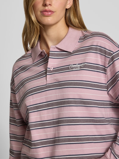 Vrouwenmodel draagt oversized poloshirt met labelstitching Model 'Bronson' van Carhartt Work In Progress van puur katoen, Nahaufnahme Oberkörper.