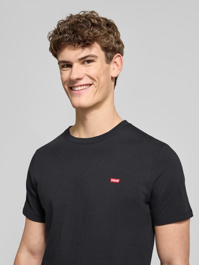 Męski model nosi T-Shirt mit Label-Stitching od Levi's®, czarny kolor, bawełna, regular fit, ściągacz, zbliżenie na górną część ciała.