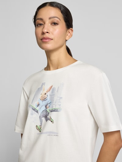 Frauenmodel trägt T-Shirt mit Motiv-Print von Marc Cain in Weiß, lockerer Schnitt aus reiner Baumwolle, Rundhalsausschnitt, Nahaufnahme Oberkörper.