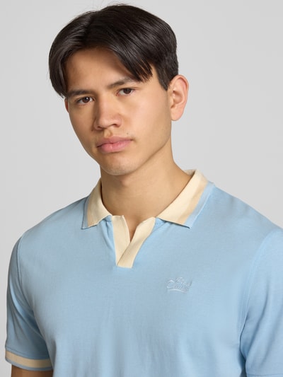 Männermodel trägt Regular Fit Poloshirt mit Label-Stitching Modell 'EVO' von Blend in Hellblau mit beigem Kragen, Nahaufnahme Oberkörper, reine Baumwolle, V-Ausschnitt.